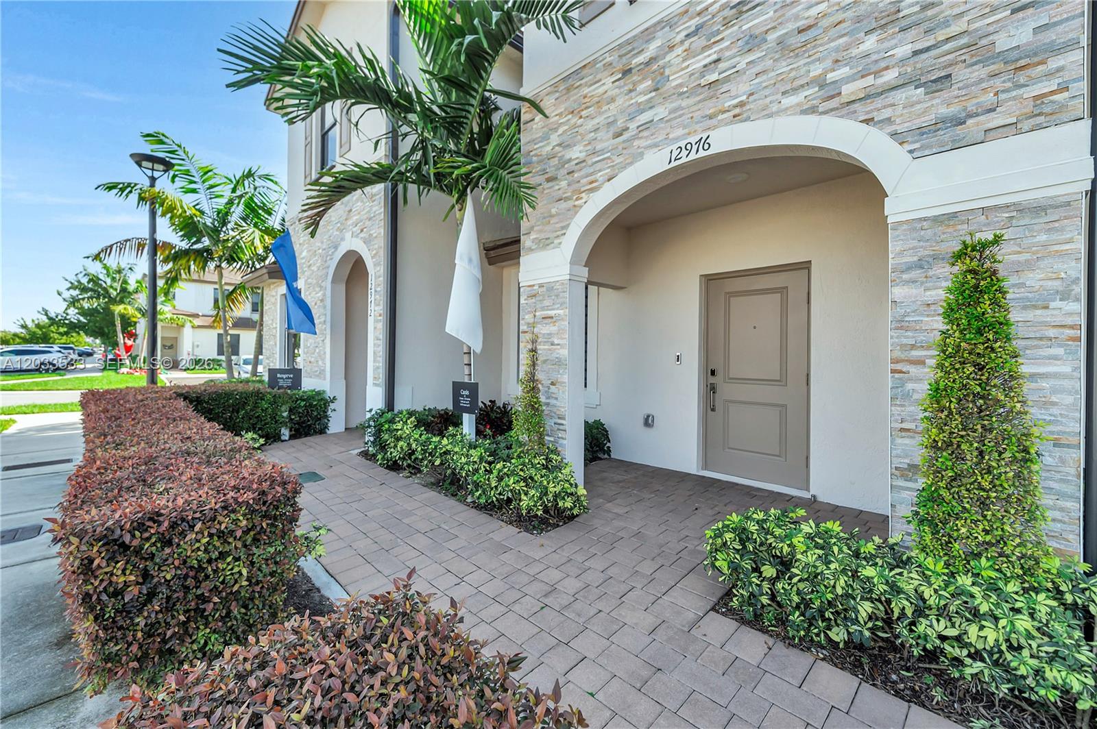 A paved walkway leads to the arched entrance of a house with stone veneer siding — 12976 SW 233rd Ter, Homestead FL 33032, HOMESTEAD, FL