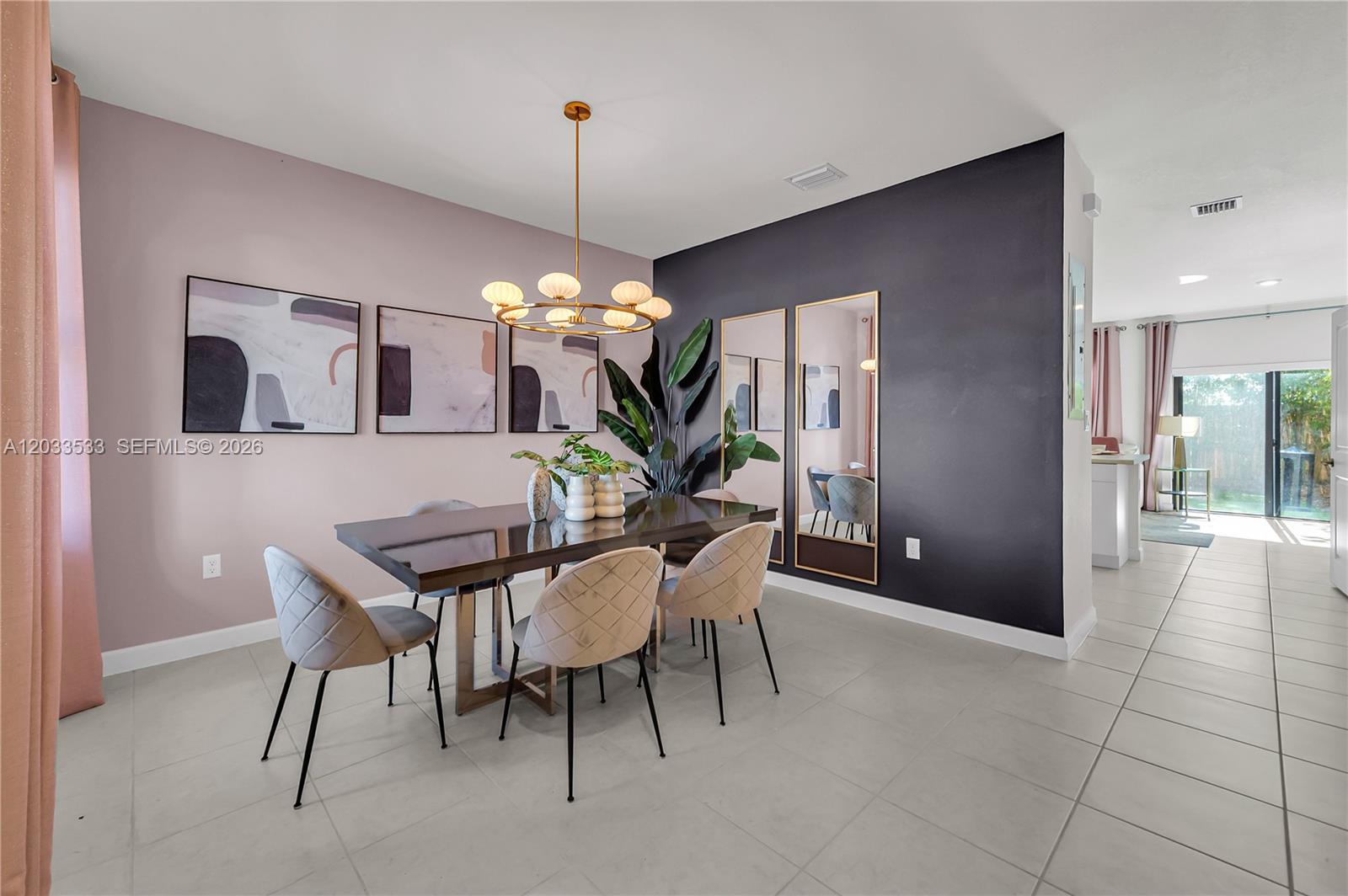 A dining room features a dark table, upholstered chairs, a chandelier, and a dark accent wall — 12976 SW 233rd Ter, Homestead FL 33032, HOMESTEAD, FL