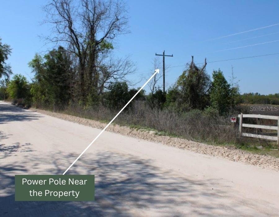 A dirt road runs alongside a grassy lot with a wooden fence and power pole — NW 50 STREET, BELL, FL