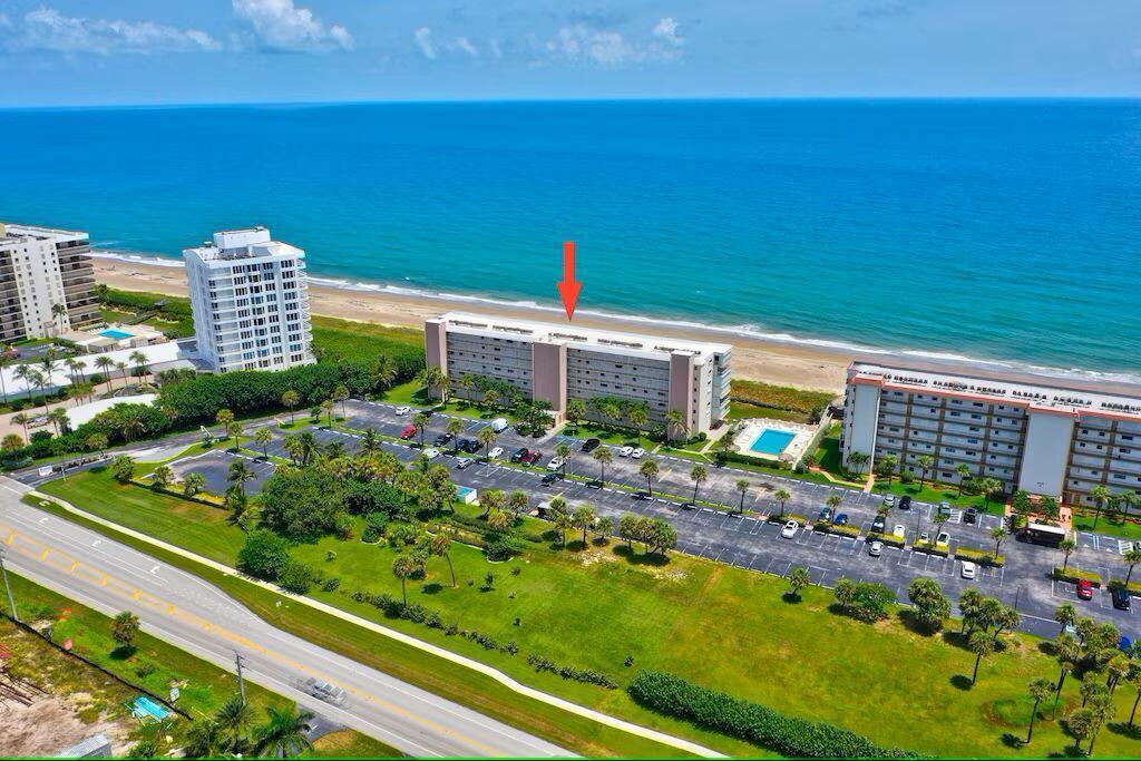 An aerial view of beachfront apartment buildings with a parking lot and surrounding green space — 10102 S Ocean Drive # 107, Jensen Beach FL 34957, JENSEN BEACH, FL