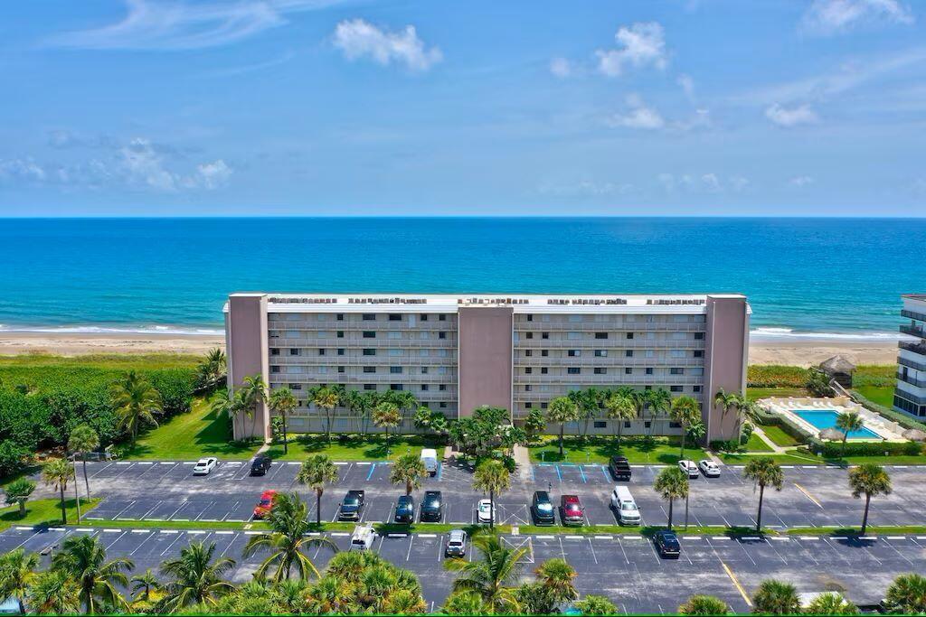 An aerial view of a multi-story apartment building situated next to a beach and ocean — 10102 S Ocean Drive # 107, Jensen Beach FL 34957, JENSEN BEACH, FL