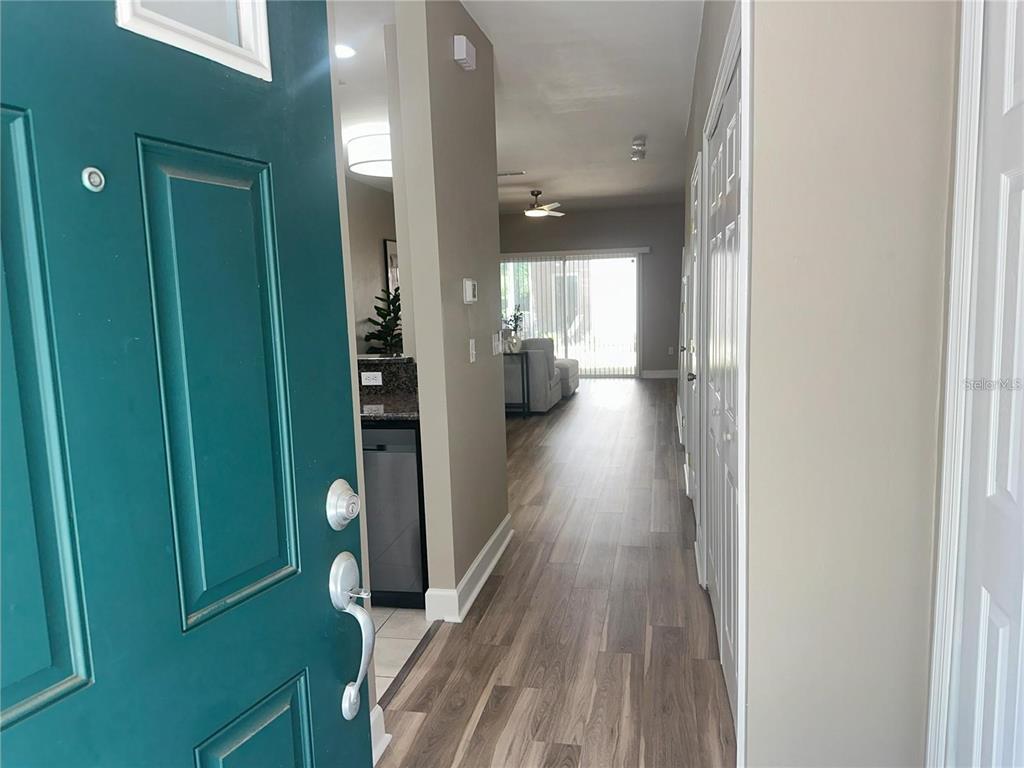 An entryway opens into a hallway with wood-look flooring leading toward a living area — 887 NW 21ST AVENUE UNIT 887, GAINESVILLE, FL