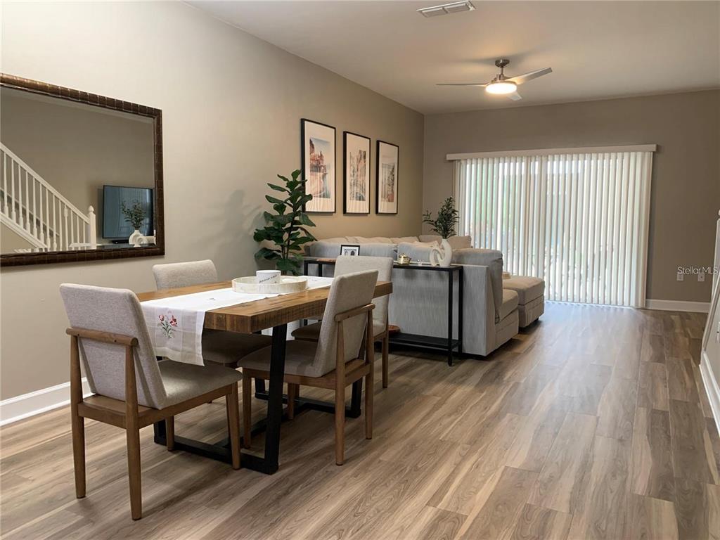 A dining area with a wooden table and chairs sits in front of a living room — 887 NW 21ST AVENUE UNIT 887, GAINESVILLE, FL