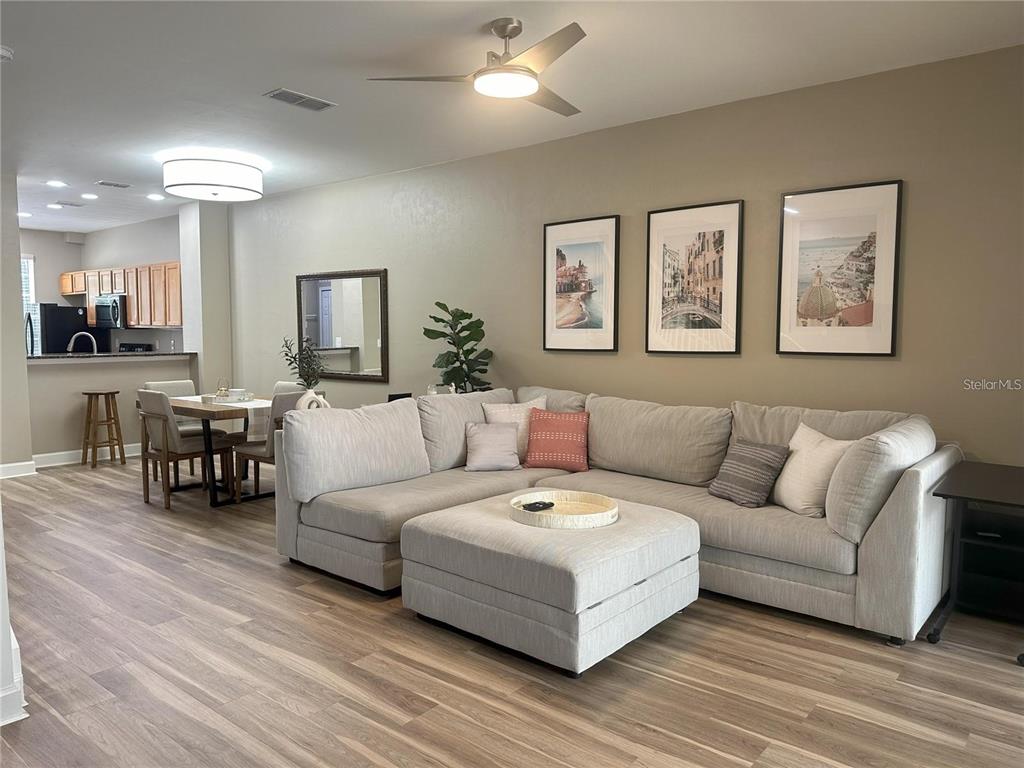 A living room features a large sectional sofa, an ottoman, and wall art — 887 NW 21ST AVENUE UNIT 887, GAINESVILLE, FL