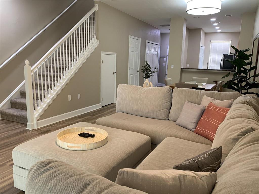 A living room features a large sectional sofa, a staircase, and an open dining area — 887 NW 21ST AVENUE UNIT 887, GAINESVILLE, FL
