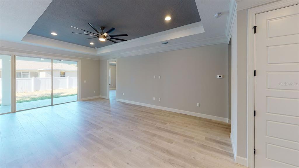 A living room features a tray ceiling with a fan, light wood floors, and sliding doors — 6782 PAIGO LANE, NORTH PORT, FL
