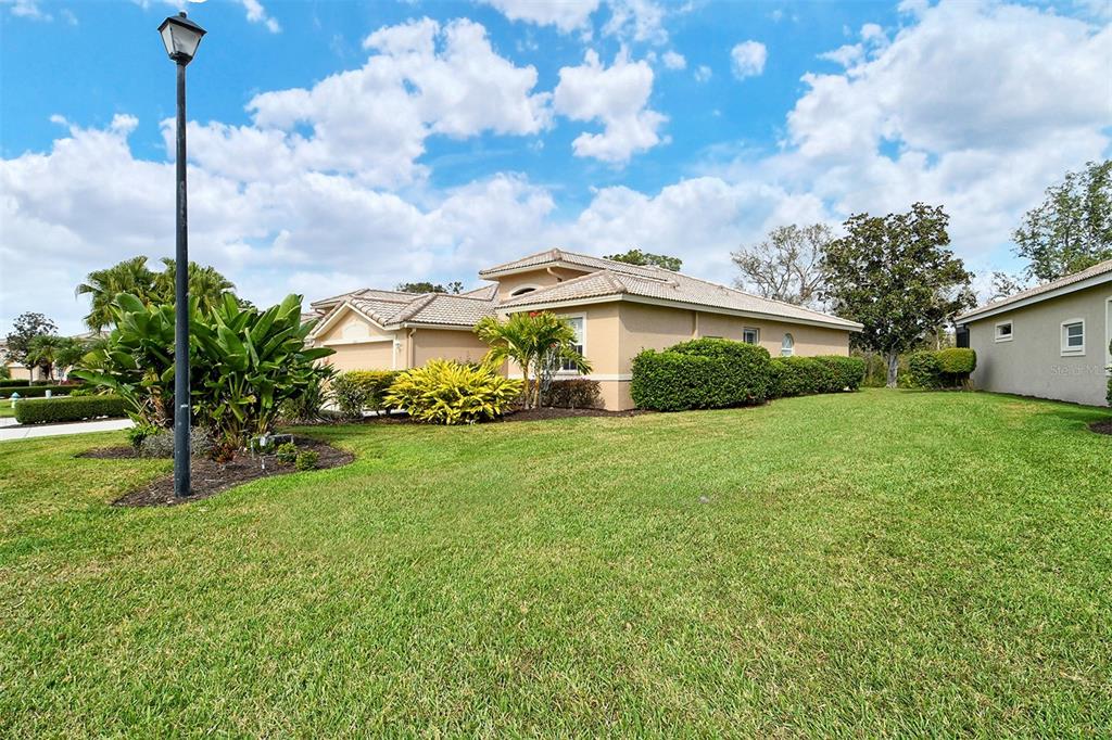 A tan single-story house with a tiled roof sits on a grassy lawn — 4516 LEGACY COURT, SARASOTA, FL