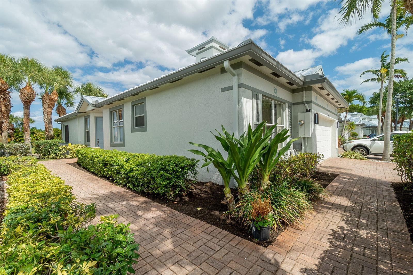 A single-story house with a white stucco exterior, a brick walkway, and tropical landscaping — 115 Coconut Key Lane, Delray Beach FL 33484, DELRAY BEACH, FL
