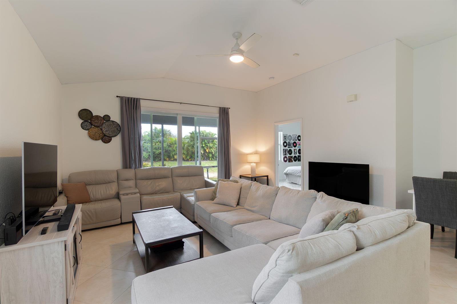 A living room features a large sectional sofa, a coffee table, and a television — 115 Coconut Key Lane, Delray Beach FL 33484, DELRAY BEACH, FL