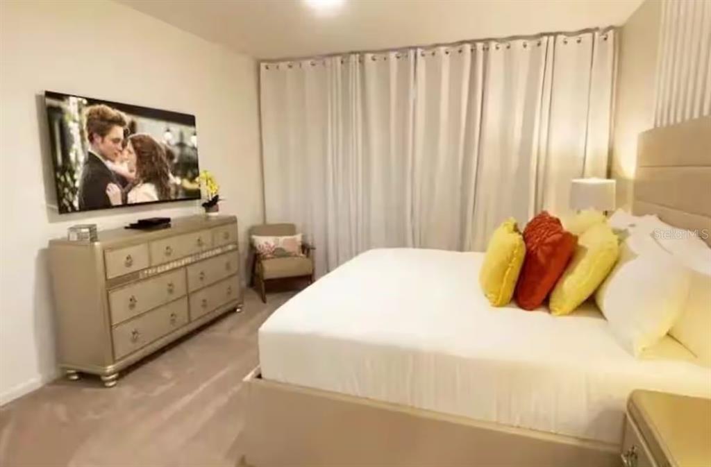 A bedroom features a bed with yellow and orange pillows, a dresser, and a television — 2484 SHANTI DRIVE, KISSIMMEE, FL