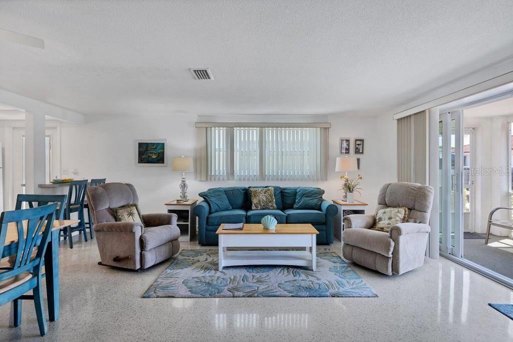 A living room features a blue sofa, two gray recliners, and light-colored terrazzo flooring — 6154 MIDNIGHT PASS ROAD UNIT A06, SARASOTA, FL