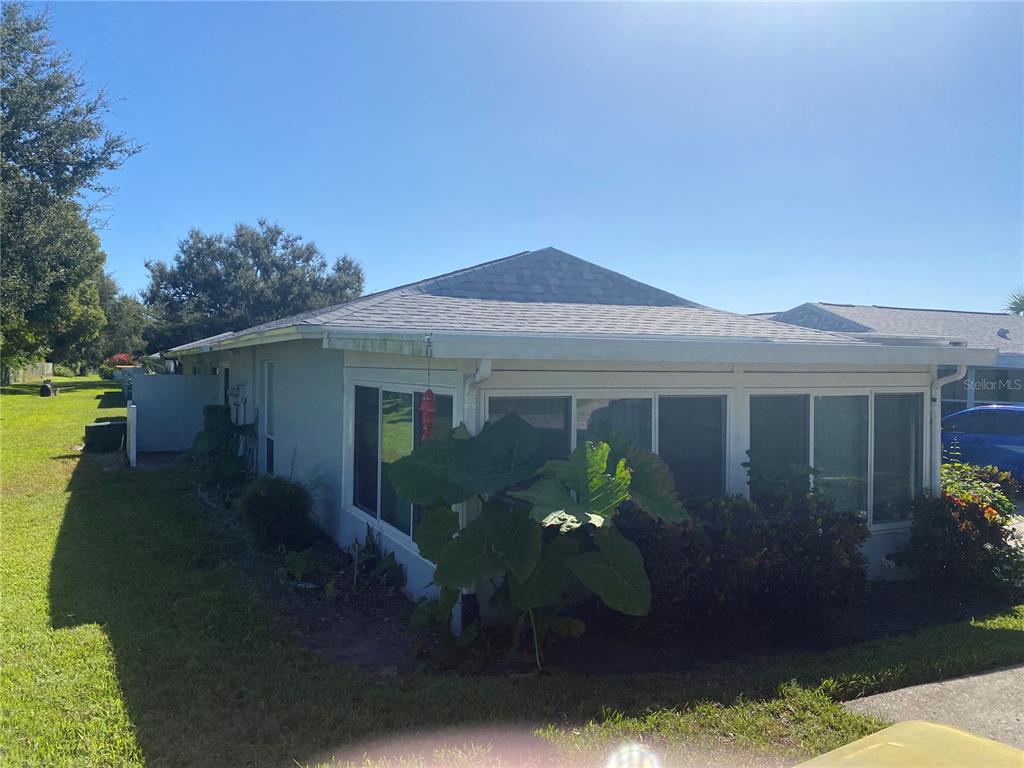 A single-story house with a screened-in porch and large tropical plants in the yard — 1609 WHITEBRIDGE DRIVE UNIT C, PALM HARBOR, FL