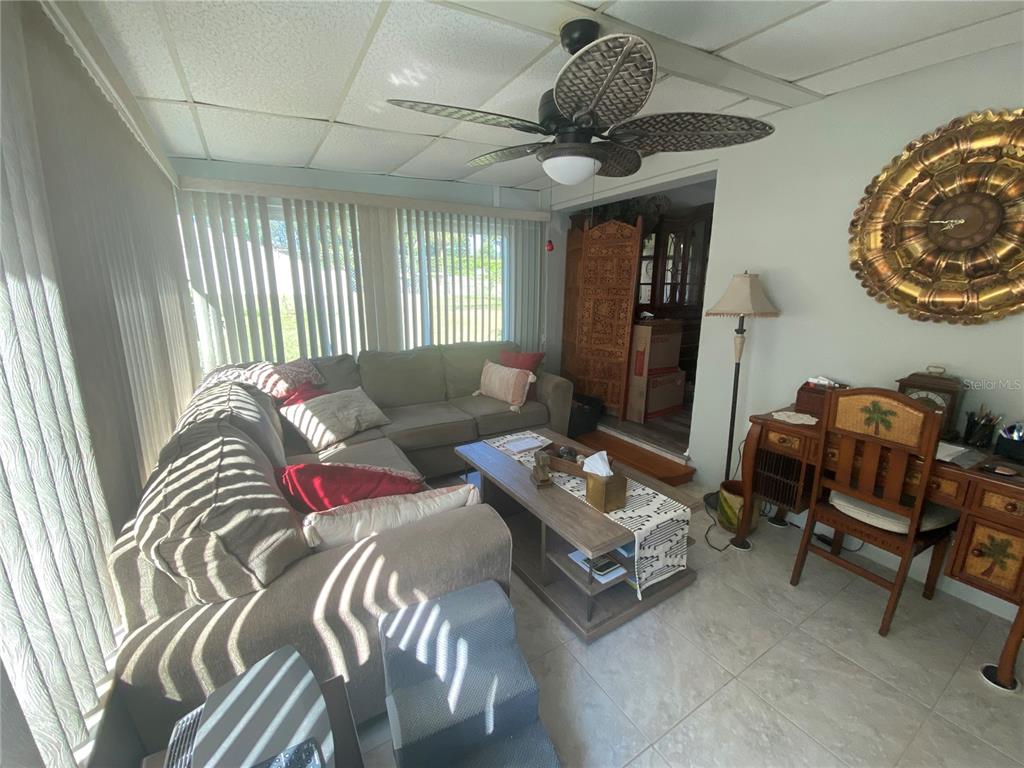 A living room features a sectional sofa, a coffee table, a ceiling fan, and tile flooring — 1609 WHITEBRIDGE DRIVE UNIT C, PALM HARBOR, FL