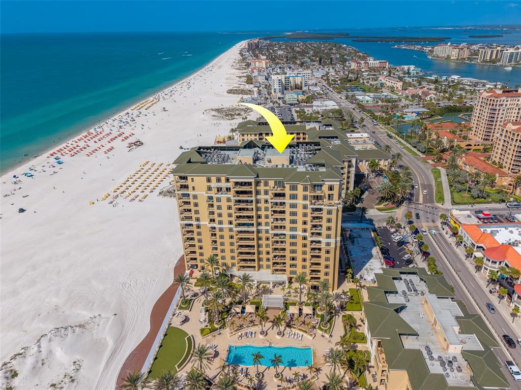 An aerial view shows a large beachfront condominium complex with a pool and parking — 11 BAYMONT STREET UNIT 1109, CLEARWATER BEACH, FL