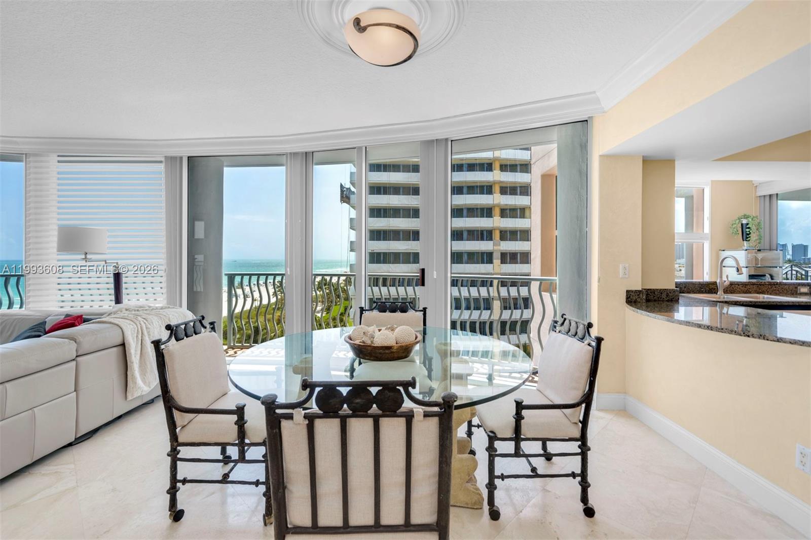 A dining area features a glass-topped table, metal chairs, and floor-to-ceiling windows overlooking the ocean — 1500 Ocean Drive # 702, Miami Beach FL 33139, MIAMI BEACH, FL