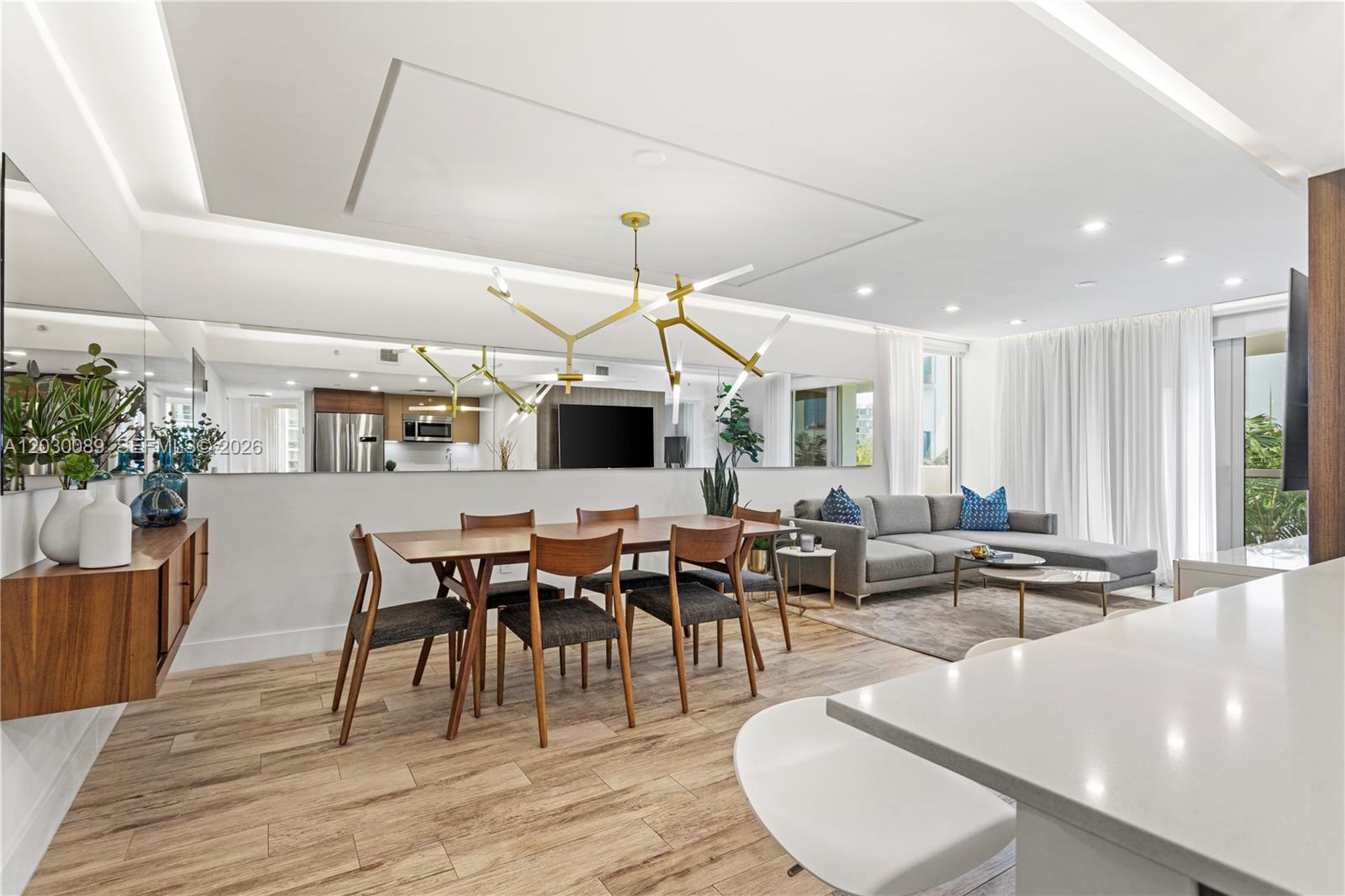 A modern open-concept living and dining area features wood-look tile flooring and a gold chandelier — 9261 E Bay Harbor Dr # 407, Bay Harbor Islands FL 33154, BAY HARBOR ISLANDS, FL