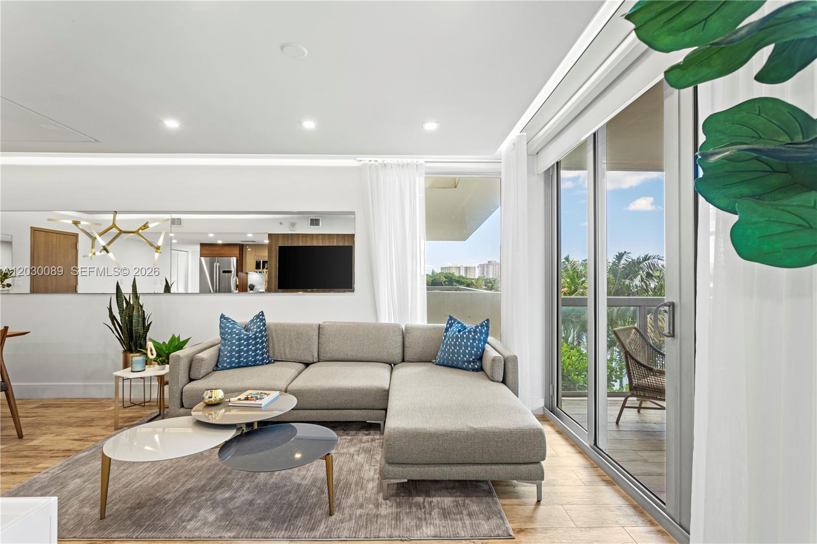 A living room features a grey sectional sofa, nested coffee tables, and a sliding glass door — 9261 E Bay Harbor Dr # 407, Bay Harbor Islands FL 33154, BAY HARBOR ISLANDS, FL