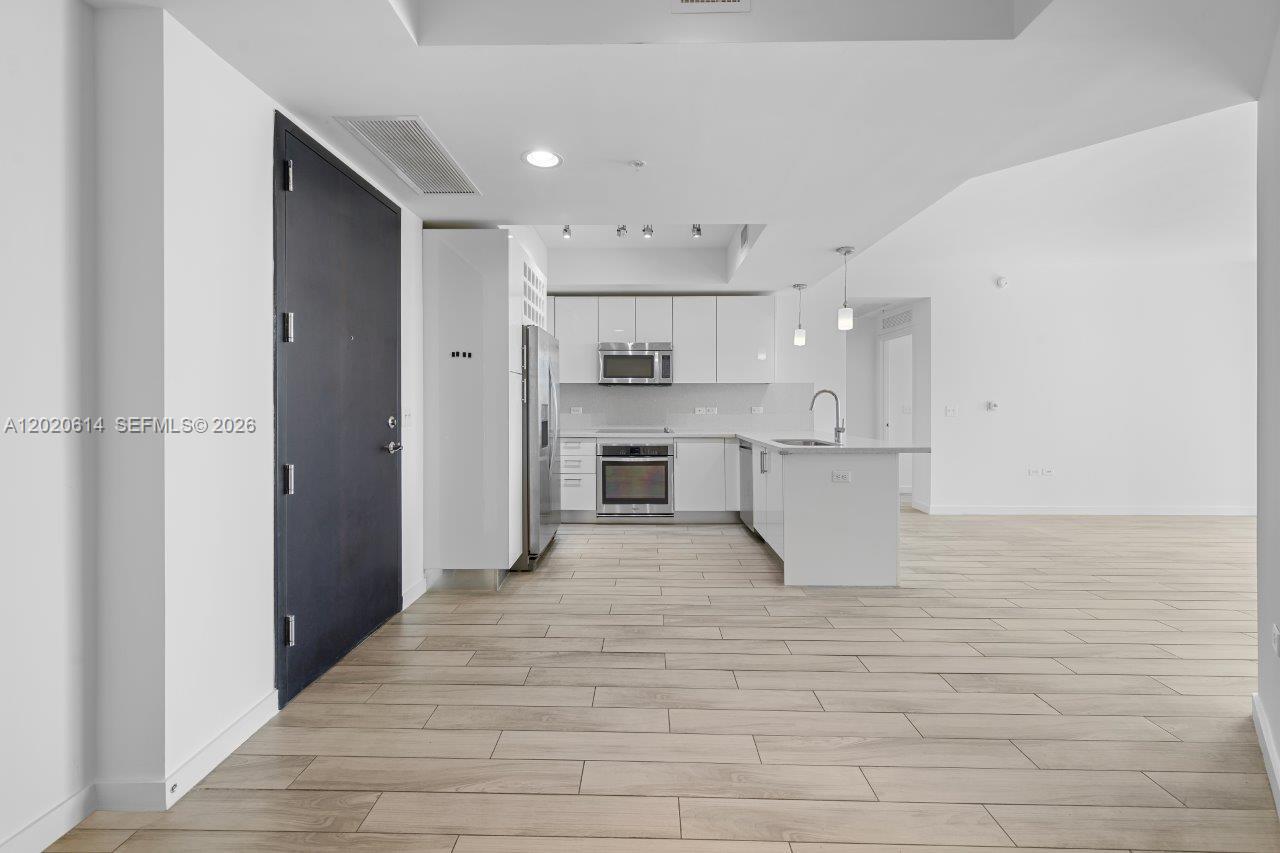 This kitchen features white cabinetry, stainless steel appliances, and light wood-look tile flooring — 999 SW 1st Ave # 2911, Miami FL 33130, MIAMI, FL