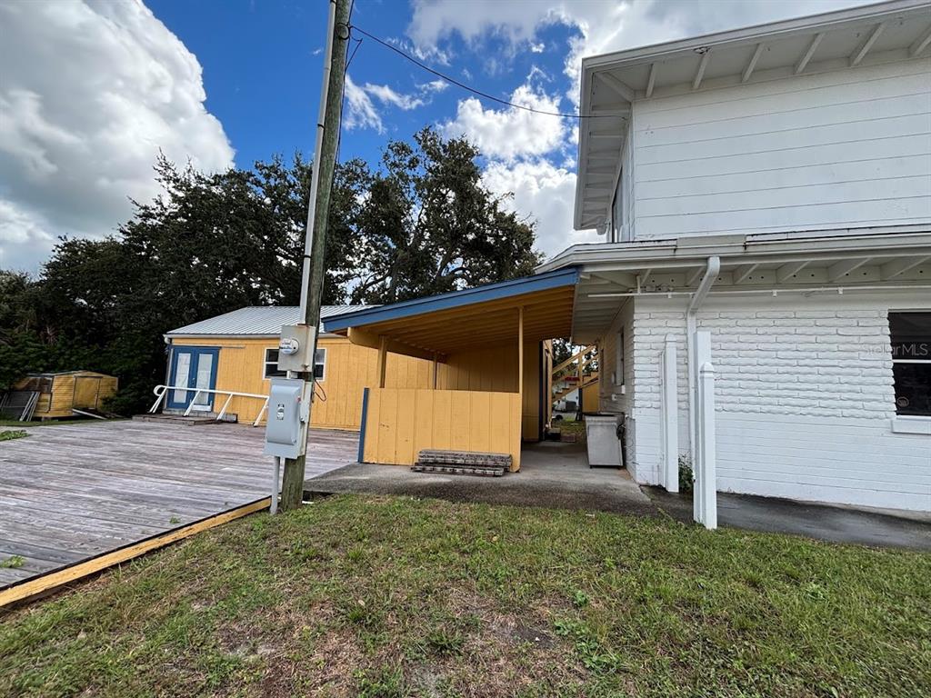 A white brick building with a yellow covered patio and an adjacent wooden deck — 1871 S RIDGEWOOD AVENUE, SOUTH DAYTONA, FL