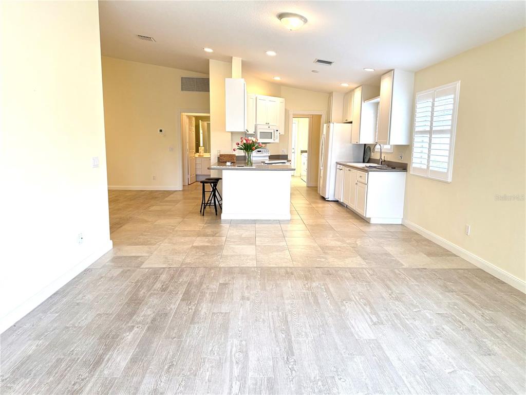 A kitchen with white cabinets and a center island opens to a tiled dining area — 6214 ERICE STREET, VENICE, FL