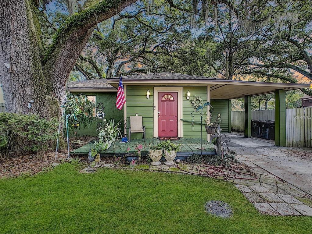 A green house with a red front door, a wooden porch, and an attached carport — 2410 E CHURCH STREET, ORLANDO, FL