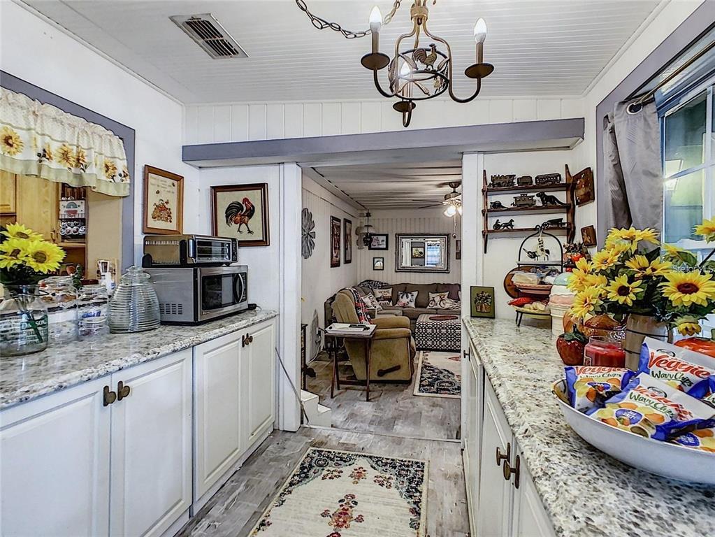 A kitchen with white cabinets and granite countertops opens into a cozy living room — 2410 E CHURCH STREET, ORLANDO, FL
