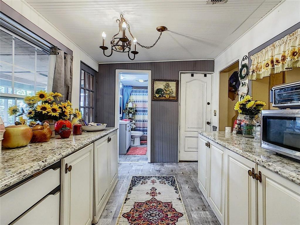 A galley-style kitchen features white cabinets, granite countertops, and a view into a bathroom — 2410 E CHURCH STREET, ORLANDO, FL