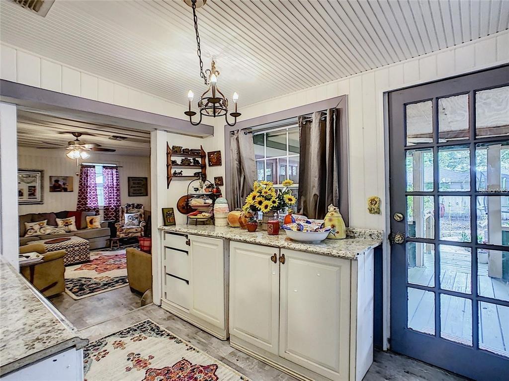 A kitchen area with white cabinets, granite countertops, and a view into a living room — 2410 E CHURCH STREET, ORLANDO, FL