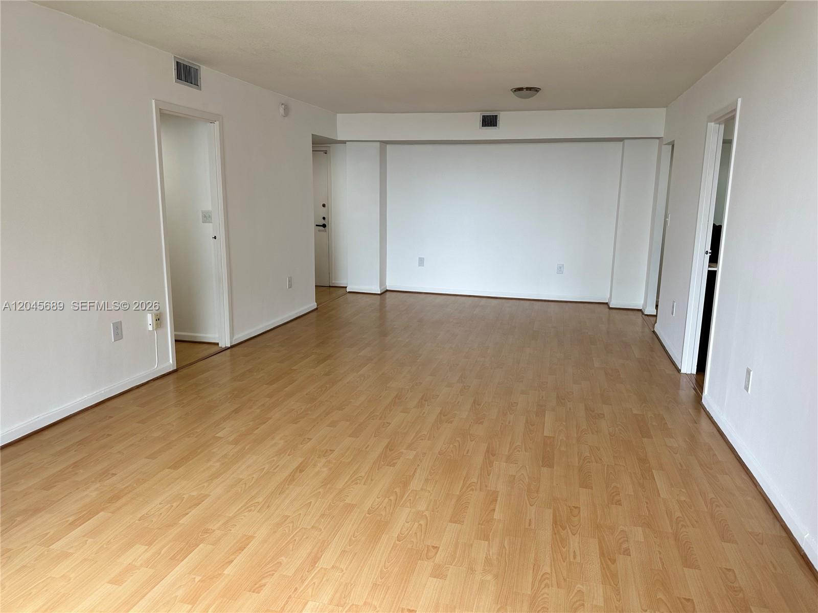 A modern kitchen features white cabinets, stainless steel appliances, and light wood flooring — 2333 Brickell Ave # 1610, Miami FL 33129, MIAMI, FL