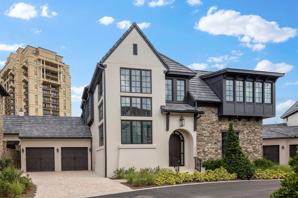 A two-story house features a stone and stucco exterior with a dark shingled roof — 10335 WINTER SPARKLE CIRCLE, GOLDEN OAK, FL