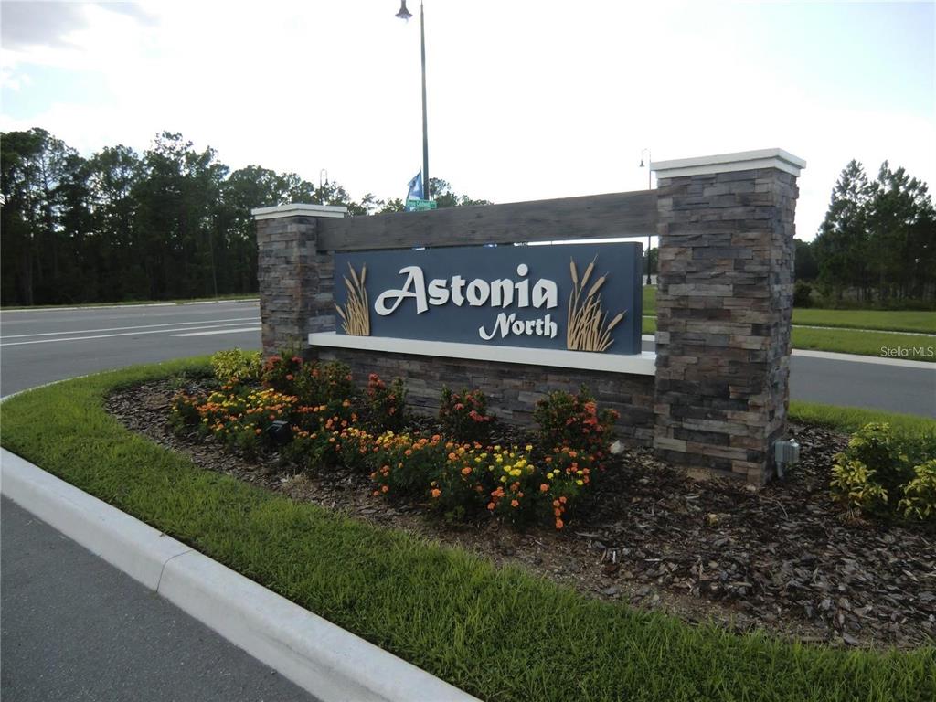 A stone and wood monument sign for Astonia North sits in a landscaped garden bed — 780 DARING DRIVE, DAVENPORT, FL