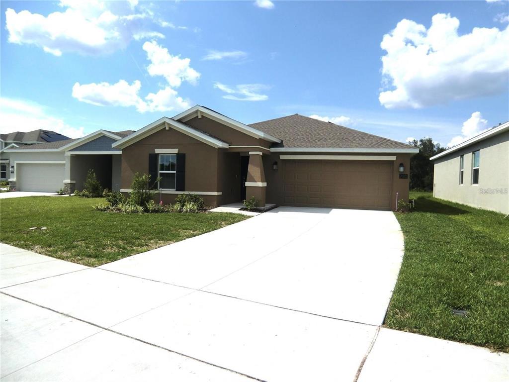 A single-story house with a brown stucco exterior, a two-car garage, and a concrete driveway — 780 DARING DRIVE, DAVENPORT, FL