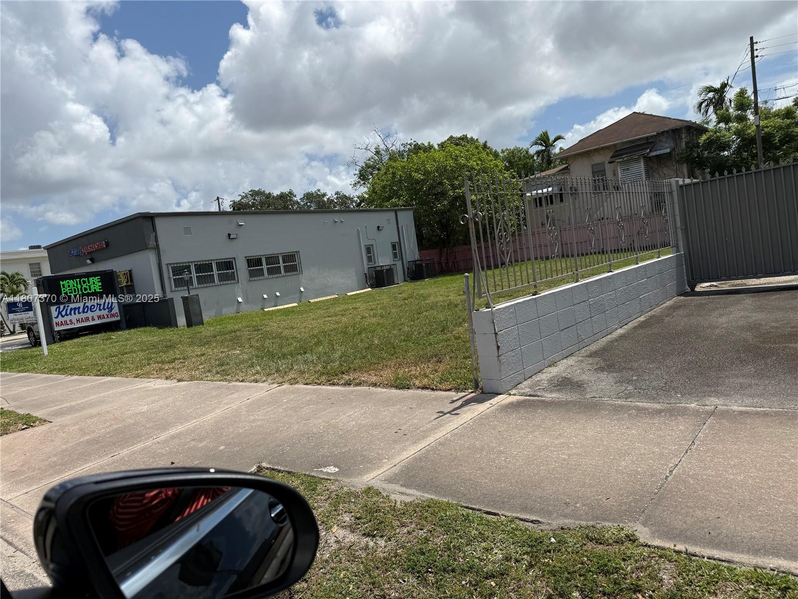 A grassy lot sits between a gray commercial building and a fenced residential property — 1959 SW 27th Ave, Miami FL 33145, MIAMI, FL