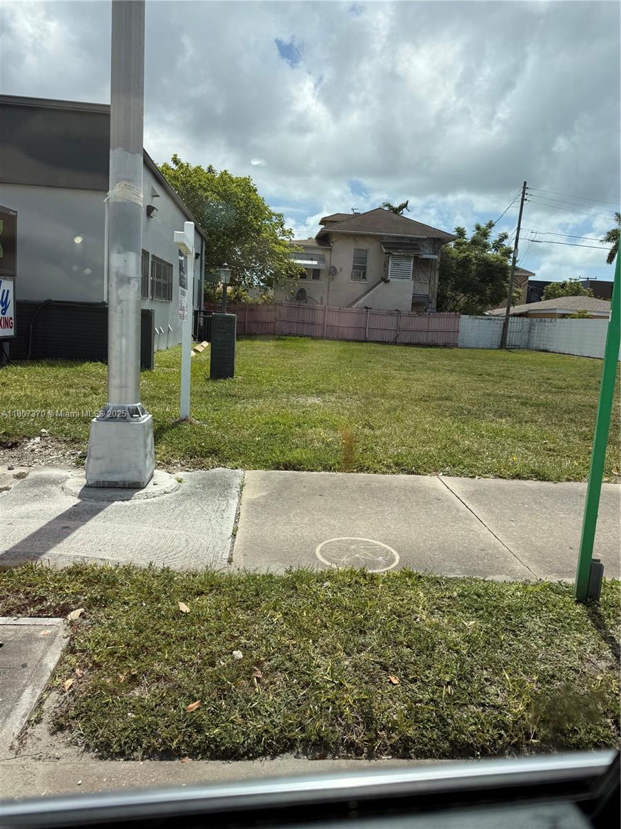 A vacant, grassy lot sits between a building and a fence under a cloudy sky — 1959 SW 27th Ave, Miami FL 33145, MIAMI, FL