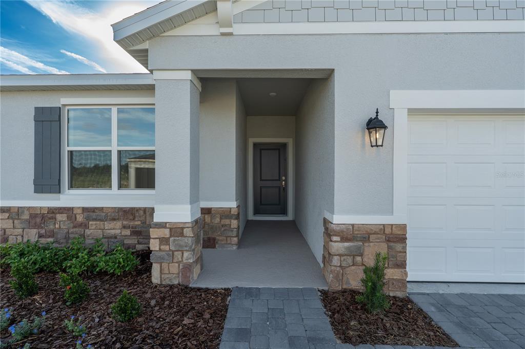 The exterior of a house features a stone-accented facade, a covered entryway, and a garage — 5844 CLIFFBOW LOOP, LEESBURG, FL