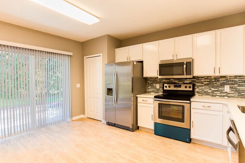 A kitchen with white cabinets, stainless steel appliances, and a sliding glass door to outside — 5879 FISHHAWK RIDGE DRIVE, LITHIA, FL