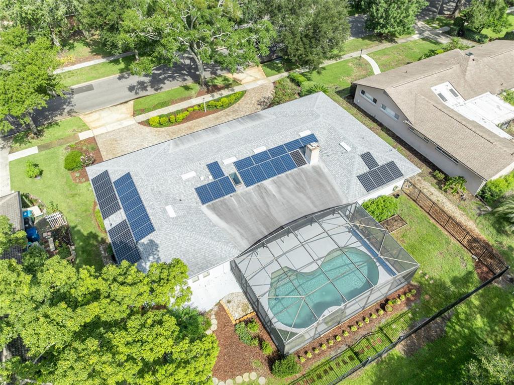 An aerial view shows a house with solar panels, a screened pool, and a large yard — 938 GOLFSIDE DRIVE, WINTER PARK, FL