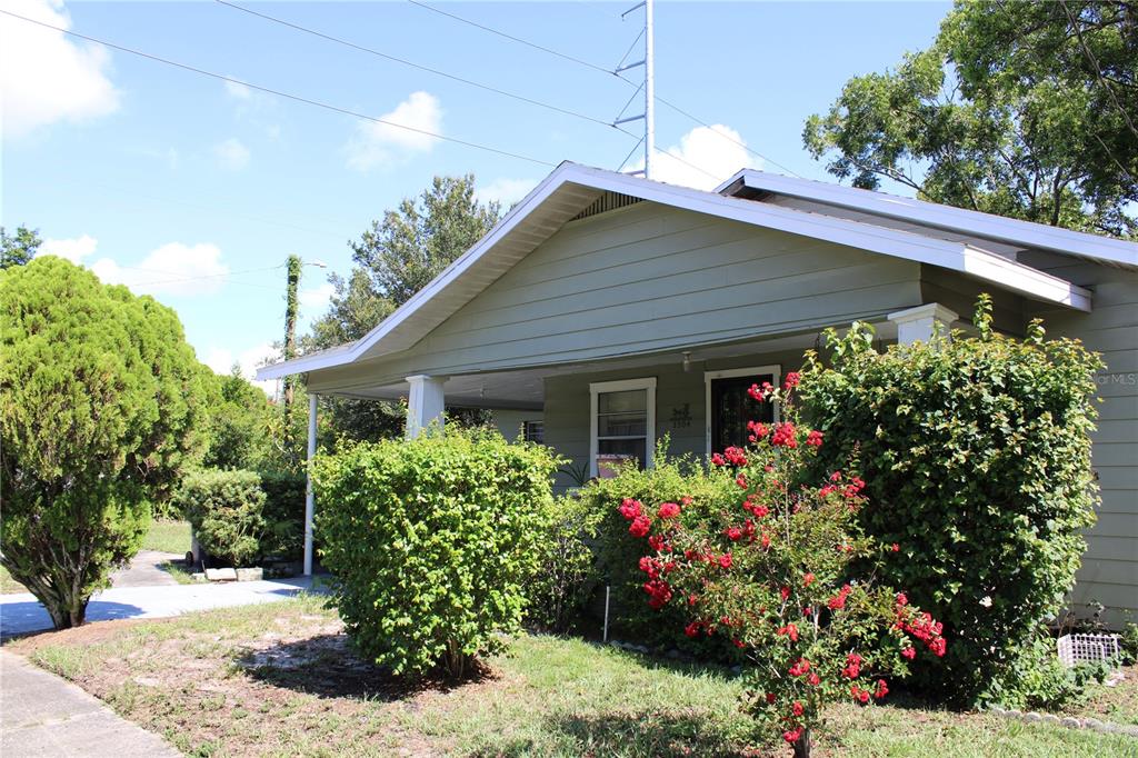 A light green house with a covered front porch and red flowering bushes — 3504 E 24TH AVENUE, TAMPA, FL