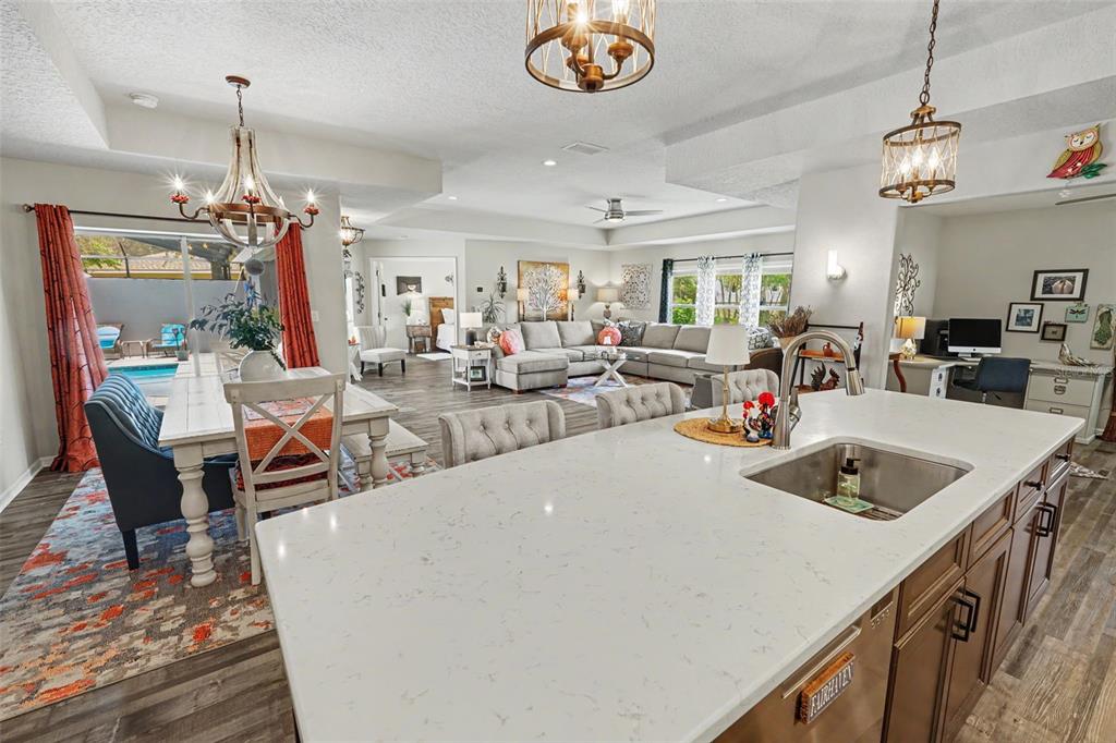 An open-concept kitchen with a quartz island overlooks a dining area and a living room — 13416 WHITMARSH STREET, SPRING HILL, FL