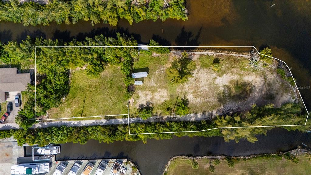 An aerial view shows a vacant, tree-lined waterfront lot with a small shed — 6141 ELLIOTT STREET, PUNTA GORDA, FL