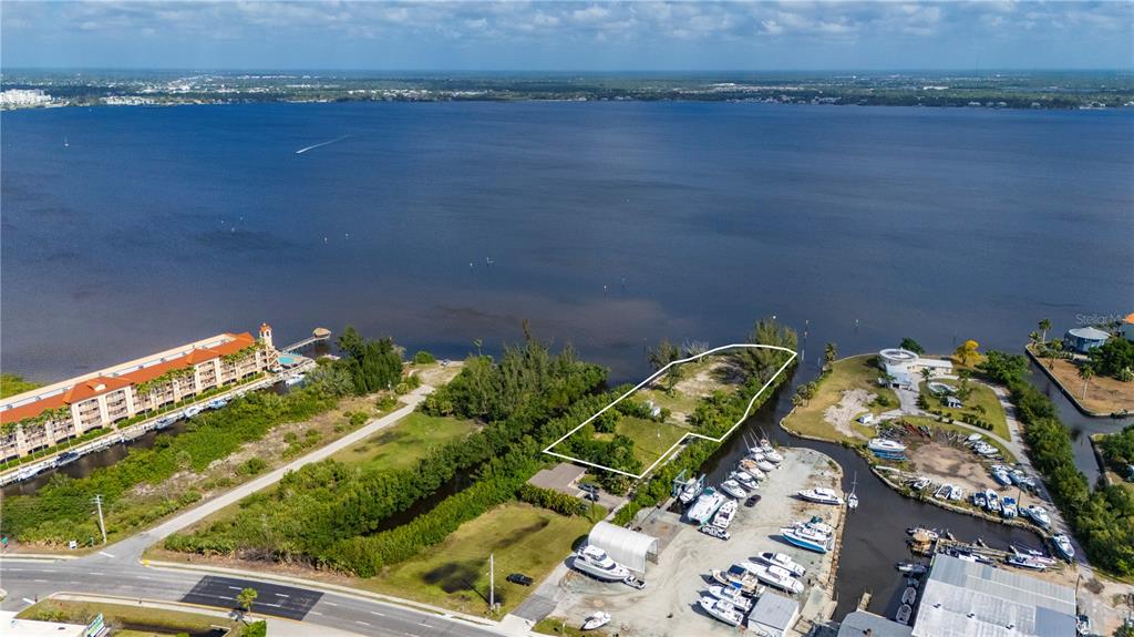 An aerial view shows a vacant waterfront lot outlined in white next to a marina — 6141 ELLIOTT STREET, PUNTA GORDA, FL