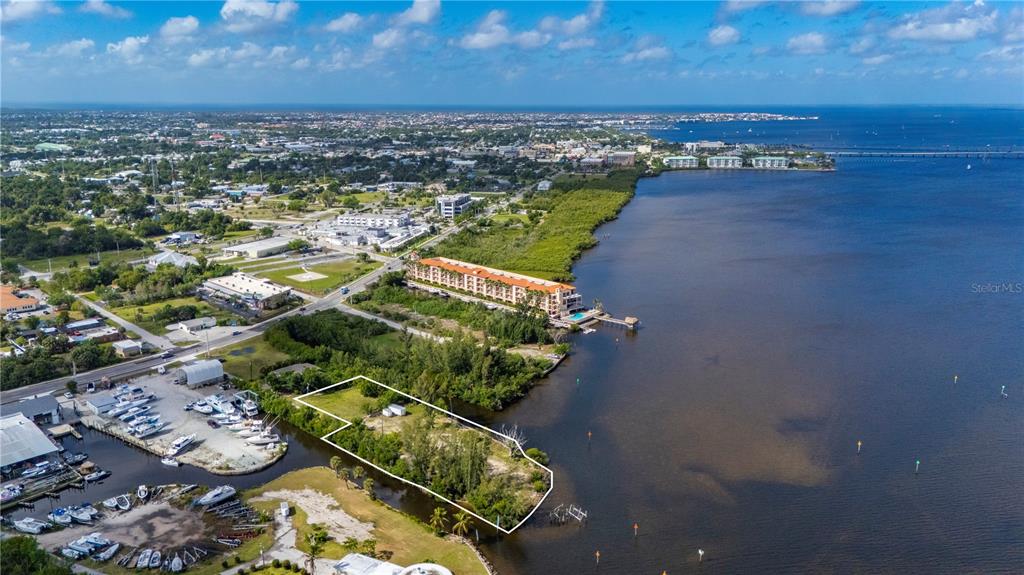 An aerial view shows a vacant waterfront lot outlined in white next to a marina — 6141 ELLIOTT STREET, PUNTA GORDA, FL