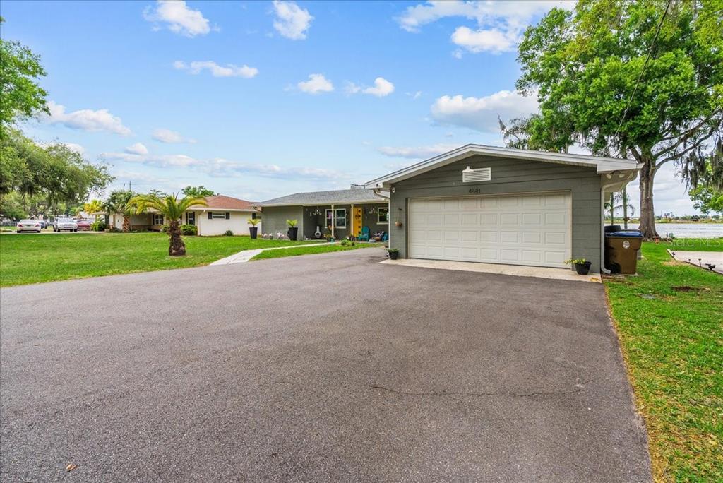 A single-story house with a gray exterior, a two-car garage, and a large asphalt driveway — 4881 LAKE CECILE DR, KISSIMMEE, FL