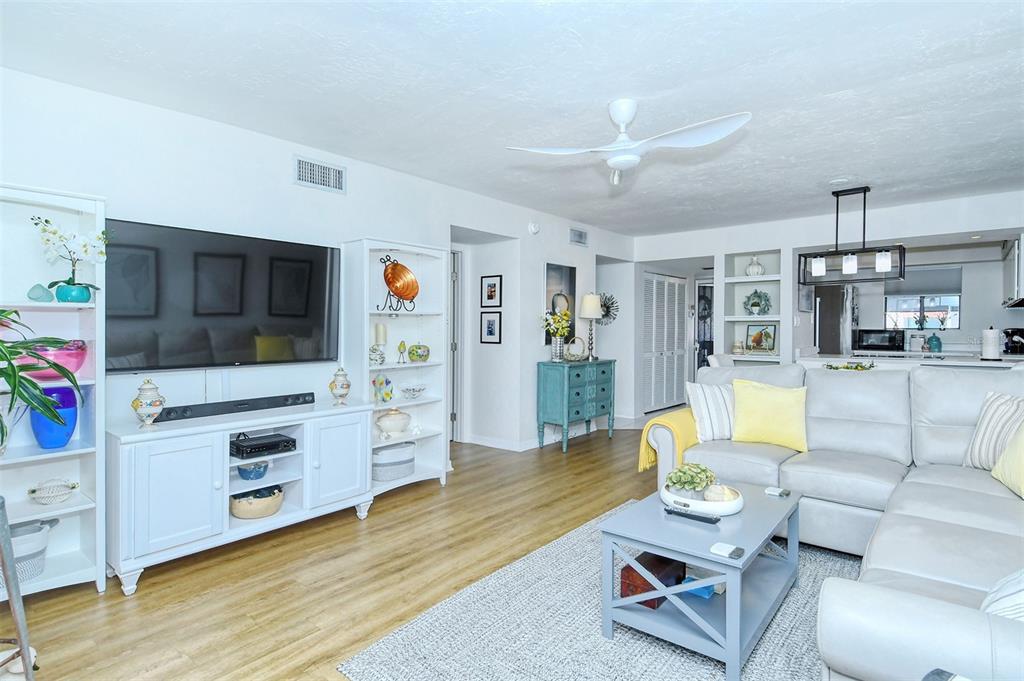A living room features a white media console, a sectional sofa, and a ceiling fan — 1801 GULF DRIVE N UNIT 275, BRADENTON BEACH, FL