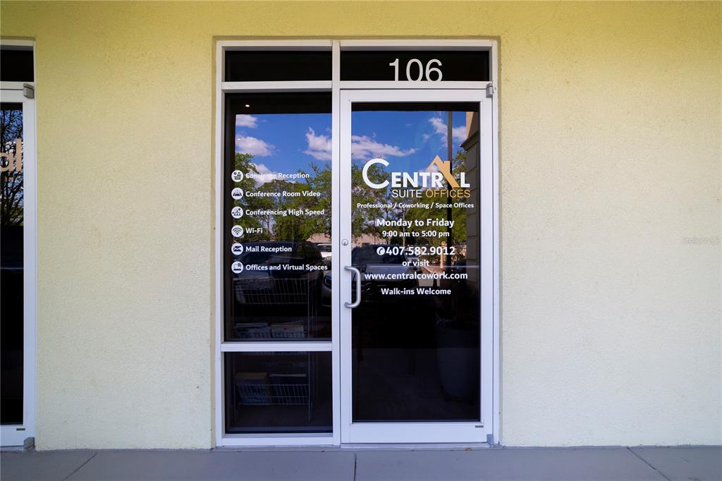 The exterior entrance of a commercial office suite features a glass door with business information — 12250 MENTA STREET UNIT 106, ORLANDO, FL