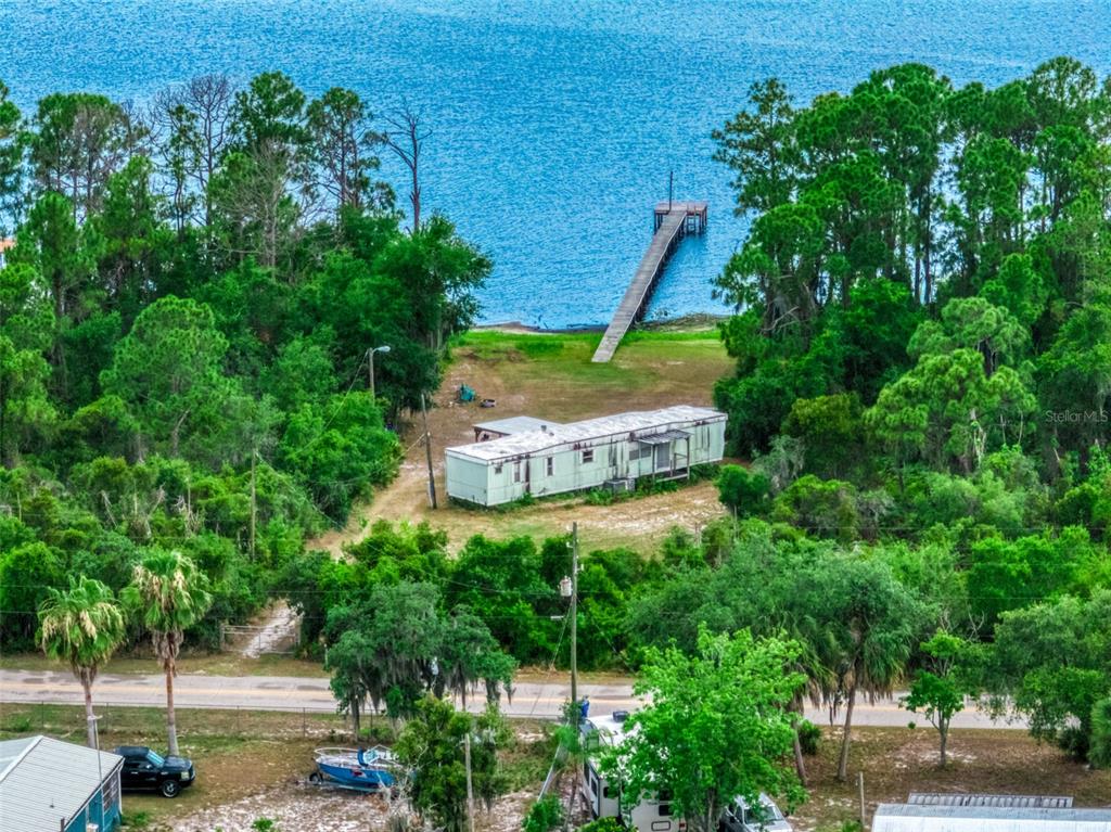 An aerial view shows a mobile home on a wooded lot with a private dock — 3144 HOLIDAY BEACH DRIVE, AVON PARK, FL