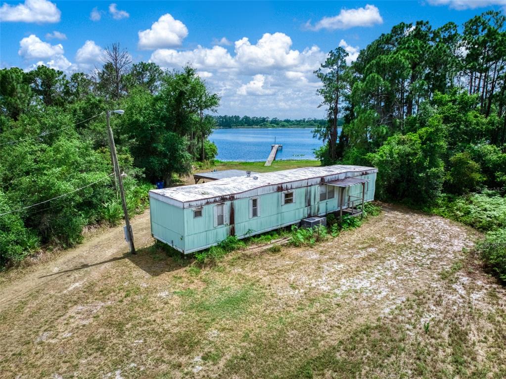An aerial view shows a weathered light green mobile home situated on a grassy lot — 3144 HOLIDAY BEACH DRIVE, AVON PARK, FL