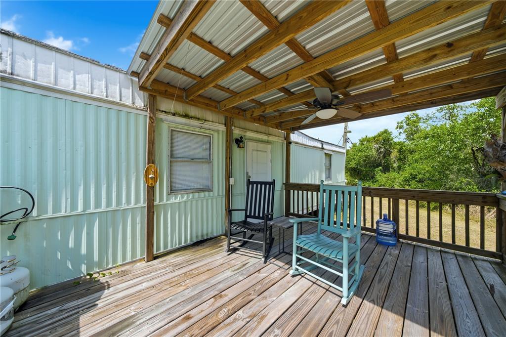 A wooden deck features two rocking chairs under a covered porch attached to a home — 3144 HOLIDAY BEACH DRIVE, AVON PARK, FL