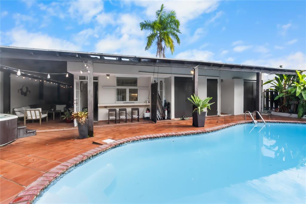 A covered patio with a bar and seating area overlooks a swimming pool — AD5 CALLE BALEARES, HUMACAO, PR