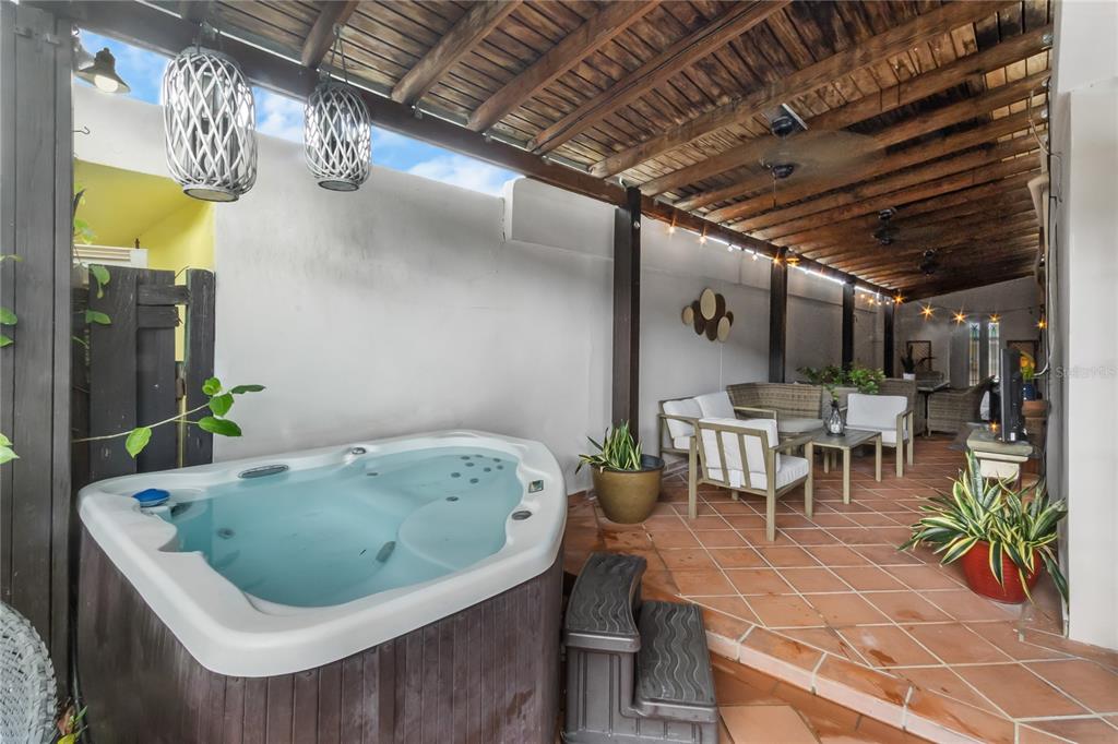 A covered patio features a hot tub, tiled flooring, and outdoor seating under a wooden ceiling — AD5 CALLE BALEARES, HUMACAO, PR